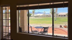A bedroom with a large bed, a window with a view of a patio, and a door with a metal gate. - Enjoy an oasis's over looking the golf course  (Fort Mohave)