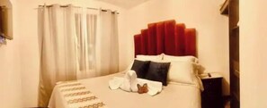 A hotel room with a bed, curtains, and a nightstand. - Casa Ire en Cuidad Vieja (Antigua Guatemala)