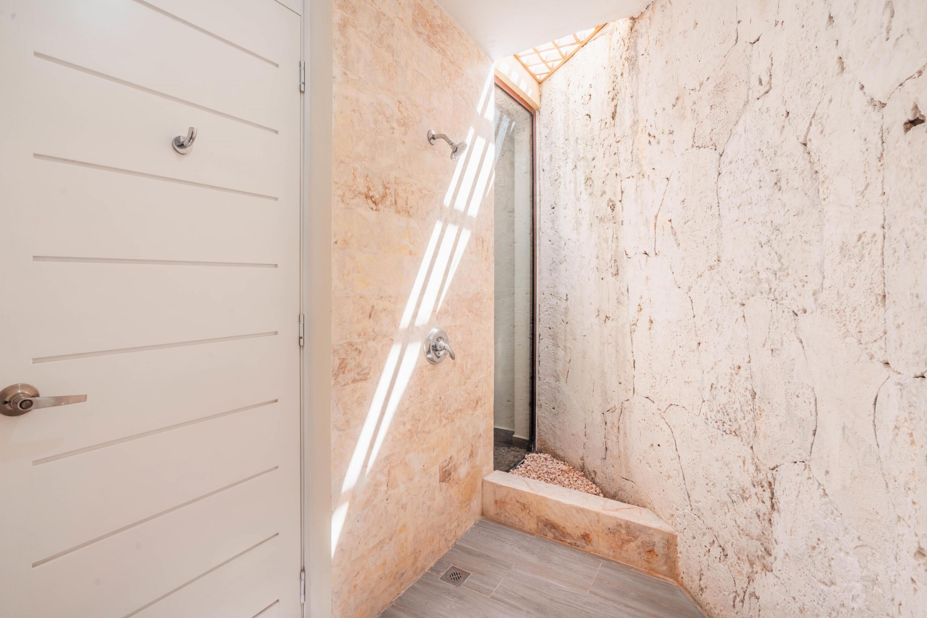 A narrow hallway with a white door on the left and a stone wall on the right.