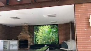A kitchen with a brick oven, a large window with a view of greenery, and a gas stove.