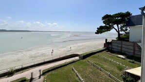 A coastal view with a sandy beach, a pathway, and a building with a tree. - Les chouettes, apartment for 4 people (Le Crotoy)