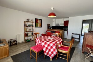 Um espaço de estar compacto com área de refeições, cozinha e estante de livros.