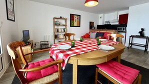 A dining area with a red and white checkered tablecloth, wooden chairs with pink cushions, and a bookshelf in the background. - Les chouettes, apartment for 4 people (Le Crotoy)