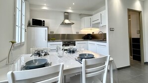 A modern kitchen with white cabinetry, a central island, and a dining area set for four.