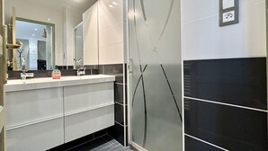 A modern bathroom with a large mirror, a shower enclosure, and a sink with a countertop.