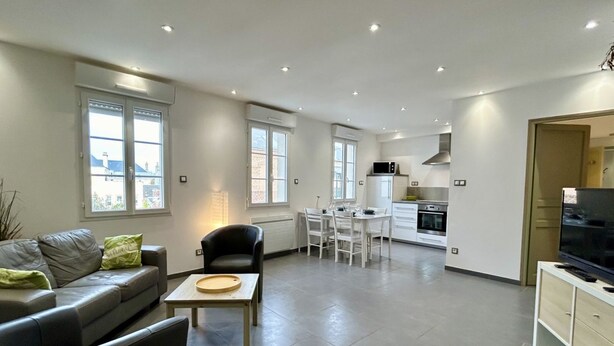 A modern apartment with a living area, kitchen, and dining space.