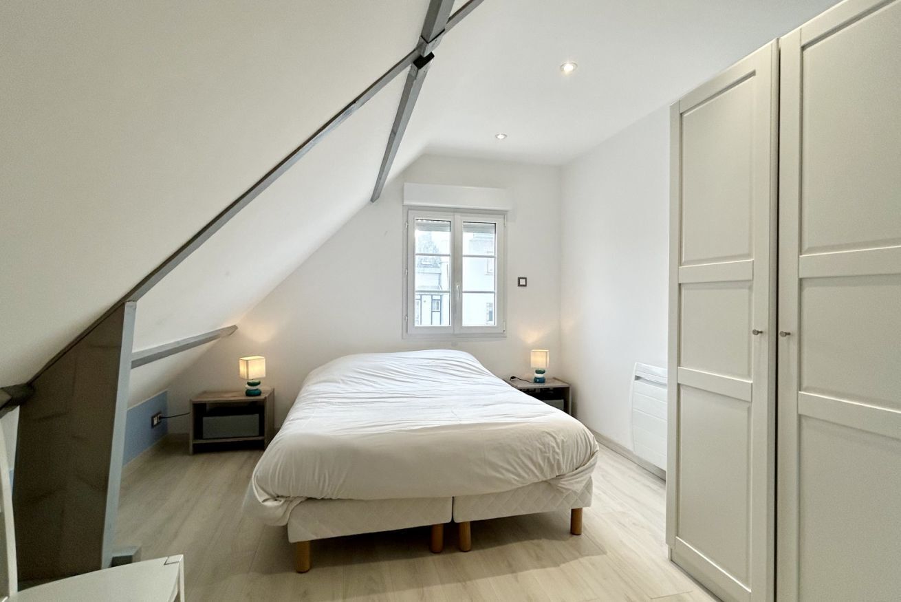Een slaapkamer met een bed, twee nachtkastjes, een raam en een kledingkast.