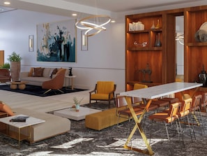 A modern living room with a sofa, chairs, a coffee table, and a dining area with a table and chairs. - Doubletree by Hilton Houston Westchase (Houston)