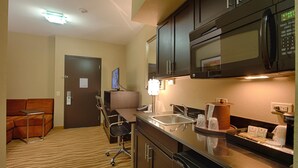 Une cuisine d’hôtel équipée d’un four à micro-ondes, d’un évier et d’un petit coin repas avec une table et des chaises.