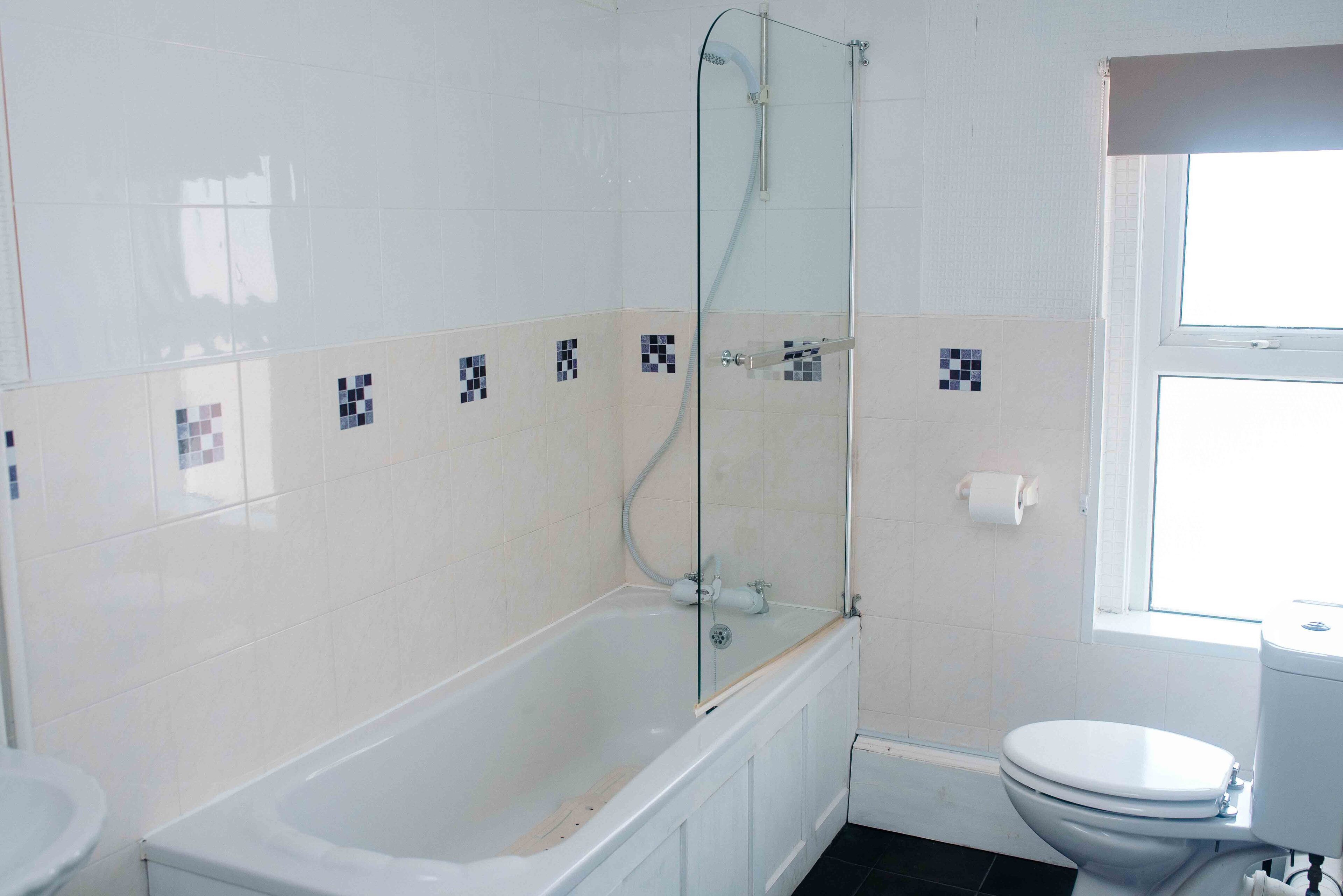 Une salle de bain avec une baignoire, des toilettes et une fenêtre.
