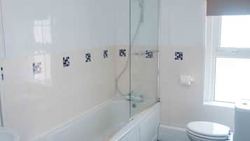 A bathroom with a bathtub, toilet, and a window.