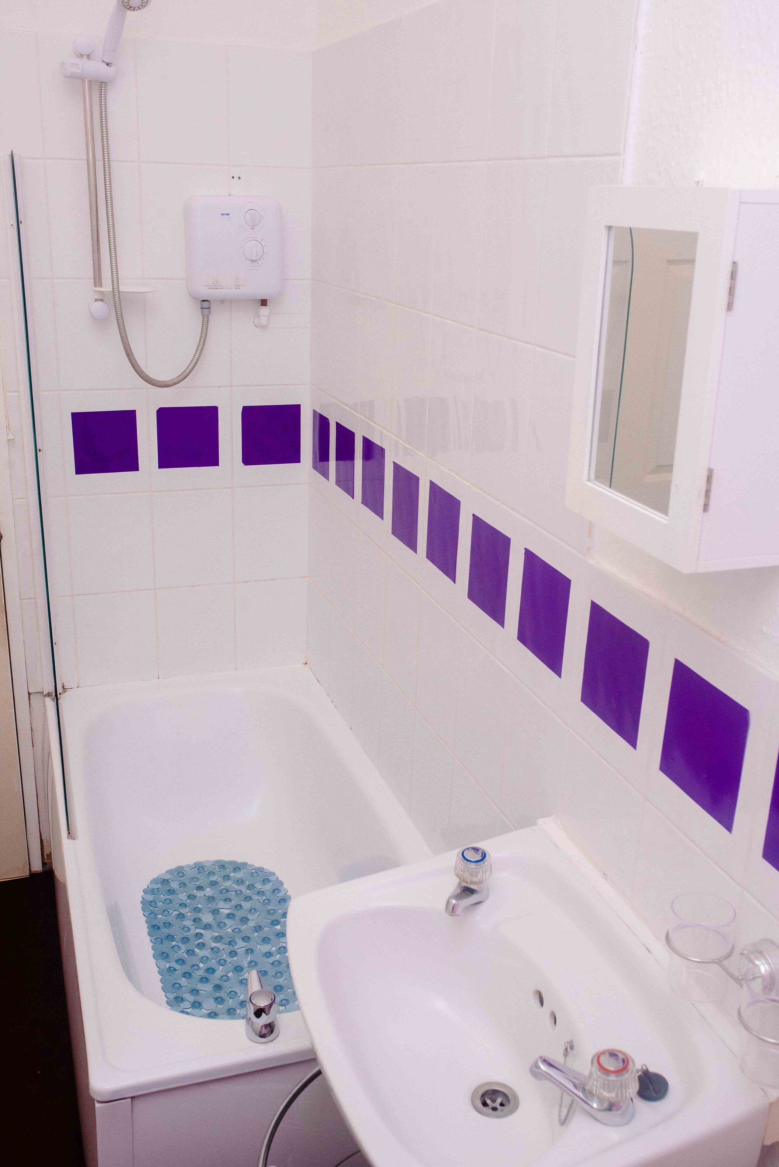 A bathroom with a bathtub, a sink, and a showerhead.