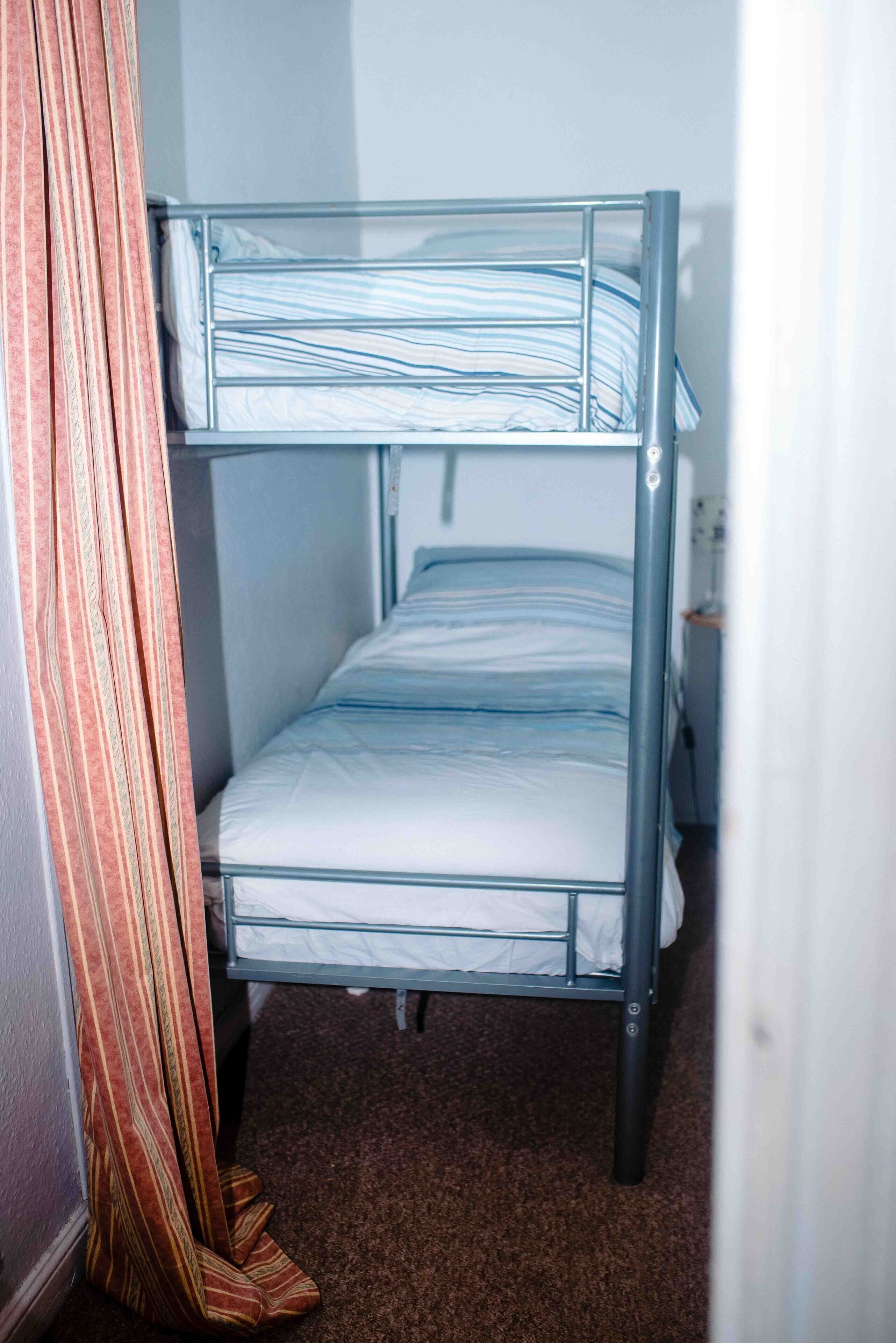 Ein Etagenbett mit Metallgestell und weißer Bettwäsche.