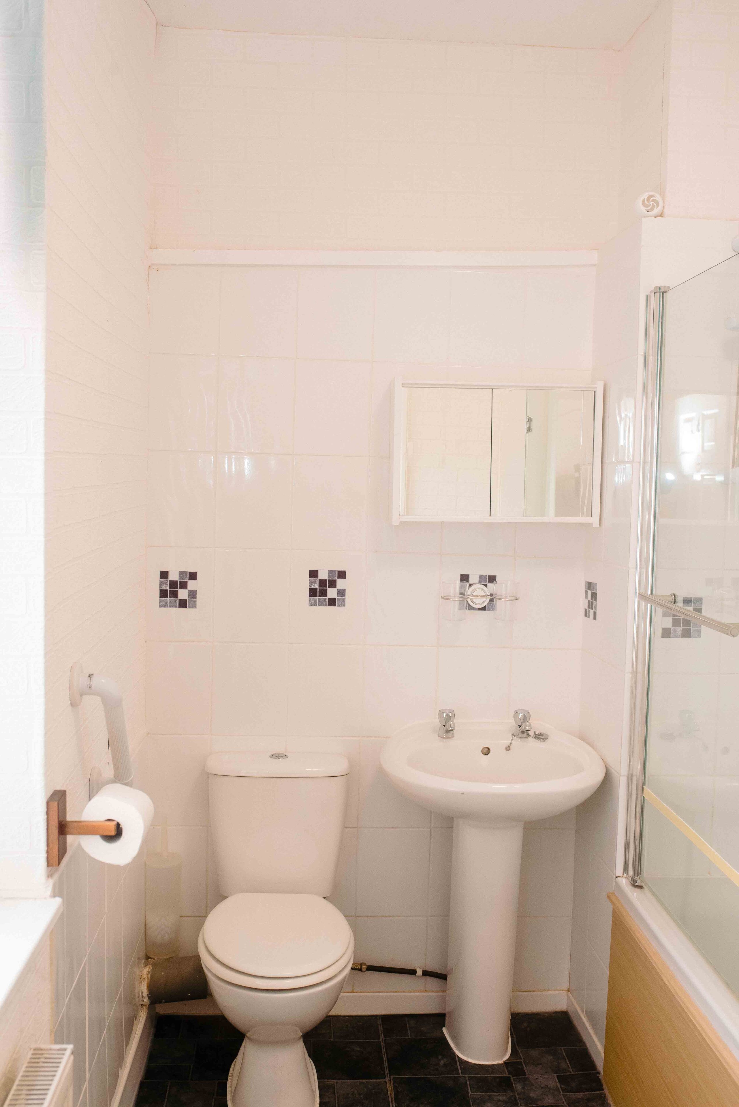 Ein kleines Badezimmer mit Toilette, Waschbecken und einer Duschkabine aus Glas.