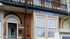 Un edificio con un cartel que dice "The Chadwick Holiday Inn" y una entrada visible con una puerta que indica "Vacantes".