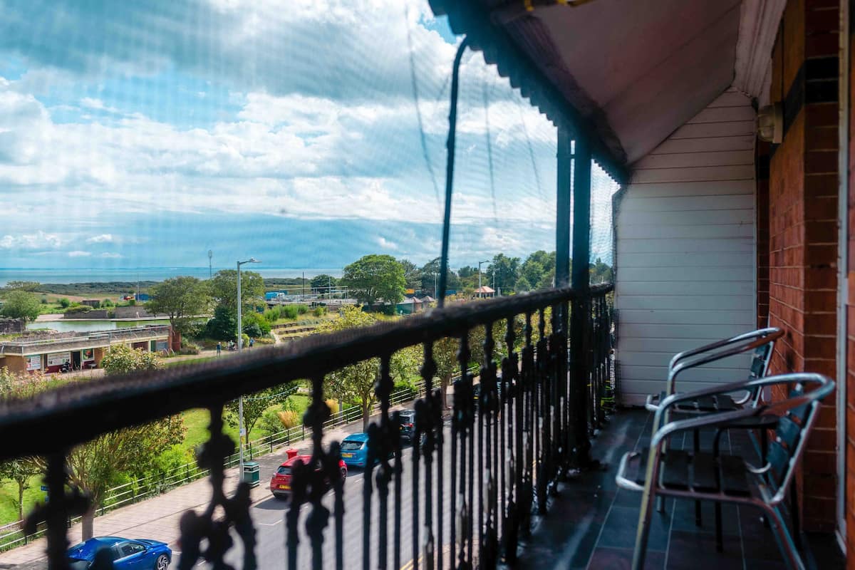A balcony with a view of a road and greenery.
