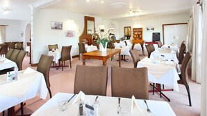 A hotel dining area with multiple tables set for guests, featuring a mix of brown and white chairs. - The Henry Parkes Tenterfield Ex Best Western (Tenterfield)