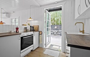 Een keuken met witte kasten, een ingebouwde oven, een koffiezetapparaat en een houten aanrecht.