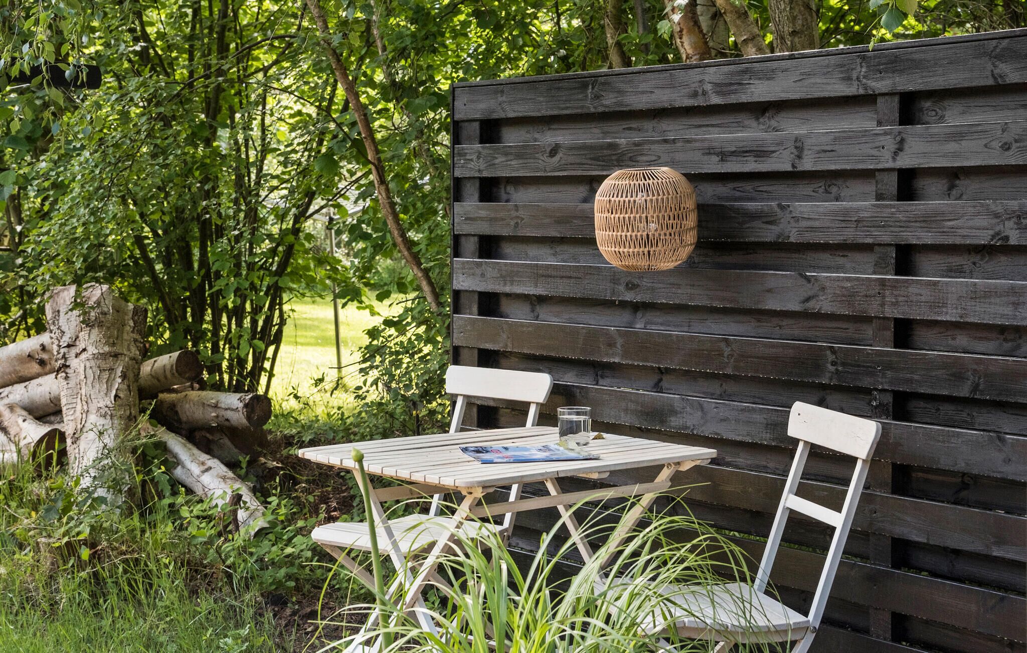 A wooden table and chairs set against a dark wooden wall with a woven basket hanging above.