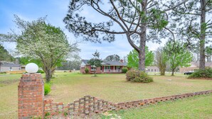 A residential area with a brick house, a lawn, and a brick wall with a spherical object on top. - Quiet & Cozy Rembert Home ~ 9 Mi to Air Force Base (Rembert)