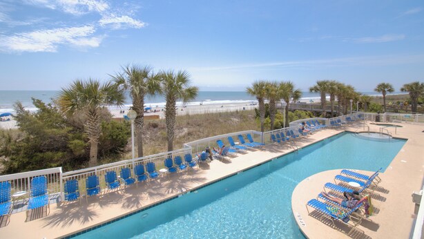A pool area with blue chairs and a view of the beach. - Oceanfront 3BR/3BA Crescent Shores North Myrtle Beach (North Myrtle Beach)