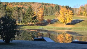 Eine friedliche Seenlandschaft mit Herbstlaub, einem Steg und einer Rasenfläche.