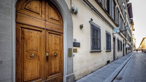 A street view with a large wooden double door, a building number sign, and a street lamp. - Hs4U Ricasoli Luxury apartment near Duomo N. 3 (Firenze)