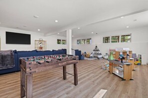 Ein geräumiges Wohnzimmer mit Tischfußball, einer Couch, einem Spielzelt und einer Spielküche.