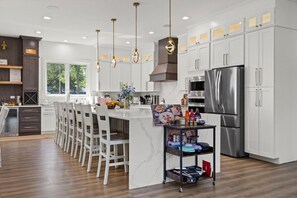 A modern kitchen with white cabinetry, stainless steel appliances, and a central island with bar stools.