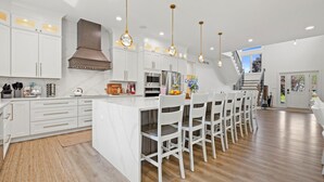 Una cocina moderna con armarios blancos, una isla central e iluminación colgante.