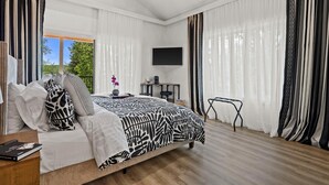 Un dormitorio con una cama grande, un televisor instalado en la pared y un escritorio con una silla.