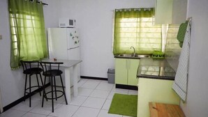 Une cuisine compacte équipée d’un réfrigérateur, d’un évier et de tabourets de bar.