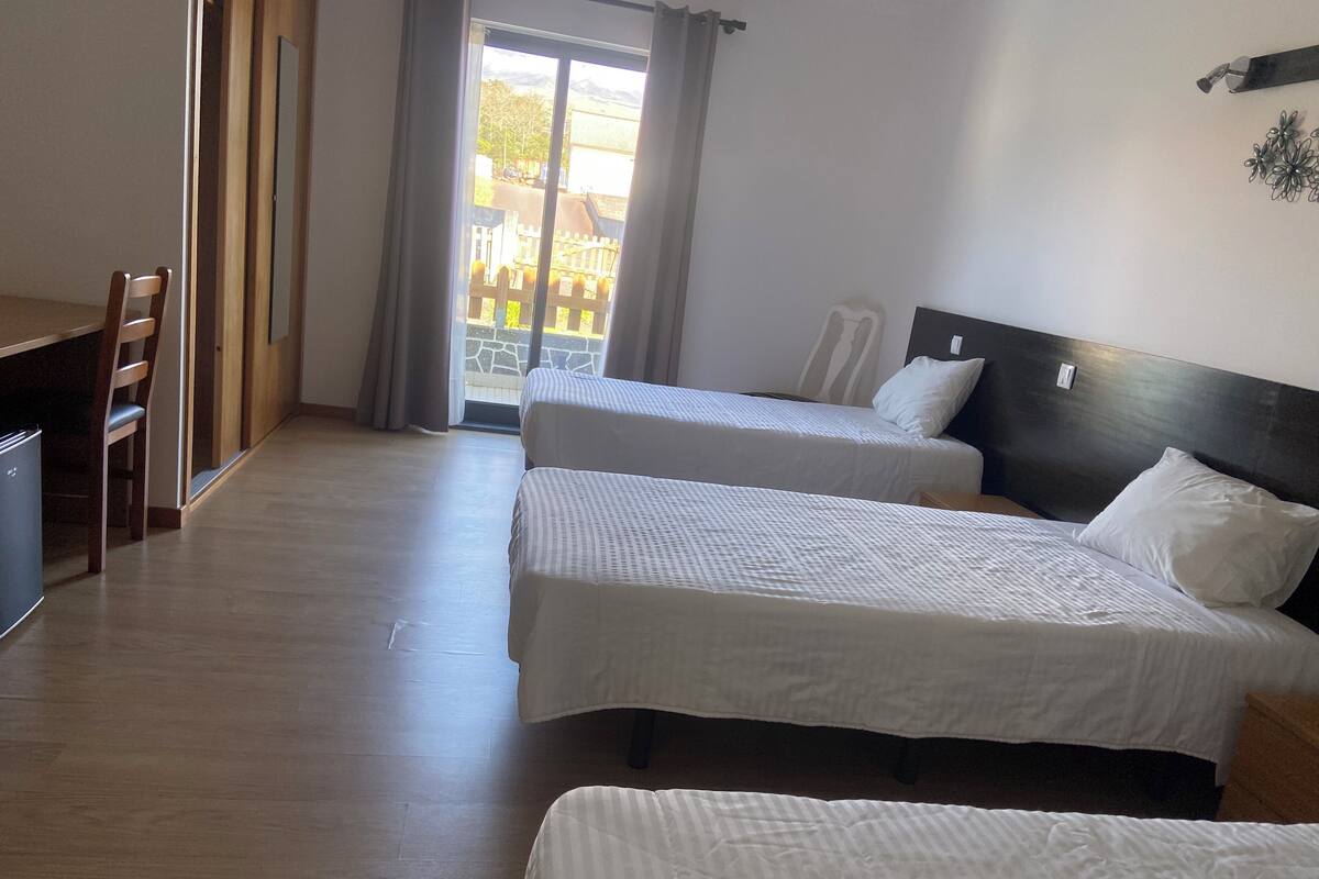 A hotel room with two beds, a desk, and a chair.