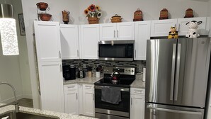 A modern kitchen with white cabinets, stainless steel appliances, and decorative items on the countertop.