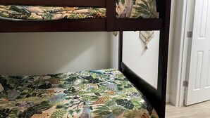 A bunk bed with a lower bunk and a top bunk, both with jungle-themed bedding.