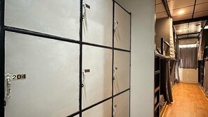 A corridor with lockers numbered 201 to 209, wooden flooring, and a ceiling with recessed lighting. - Bed Space Hostel  (Bangkok)