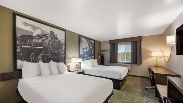 A hotel room with two beds, a desk, a chair, a lamp, and a large framed picture of a train. - Surestay by Best Western Williams - Grand Canyon (Williams)
