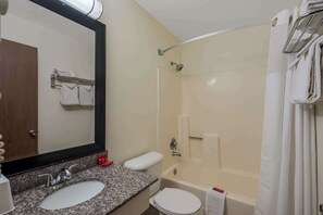 Un baño con lavamanos, espejo, inodoro y bañera.