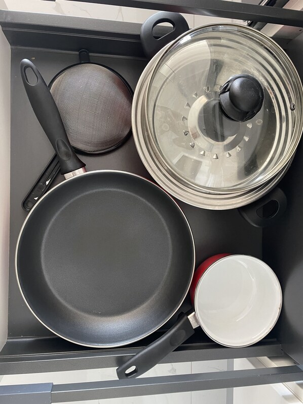 A kitchen with a stove, a frying pan, a colander, and a pot with a lid. - French Ocean View , Beach and Pool (Cul-de-Sac)