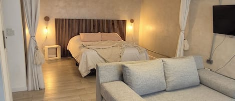 Un dormitorio moderno con una cama, un sofá y una televisión.