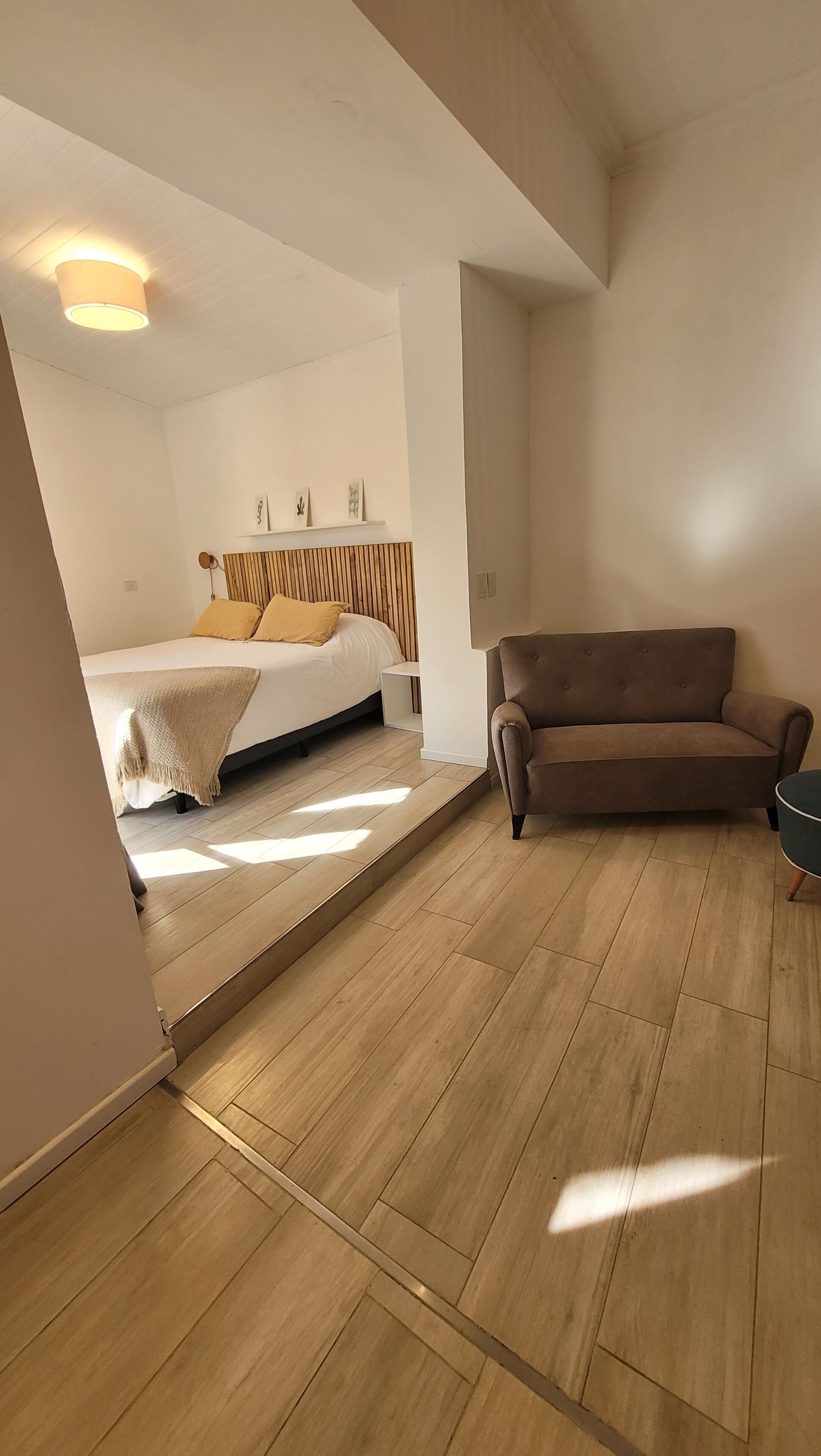 A bedroom with a bed, a sofa, and a wooden floor.