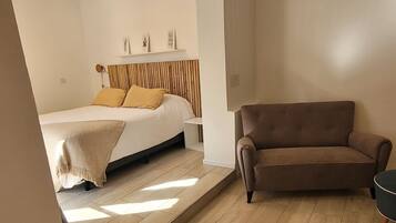 Un dormitorio con una cama, un sofá y piso de madera.