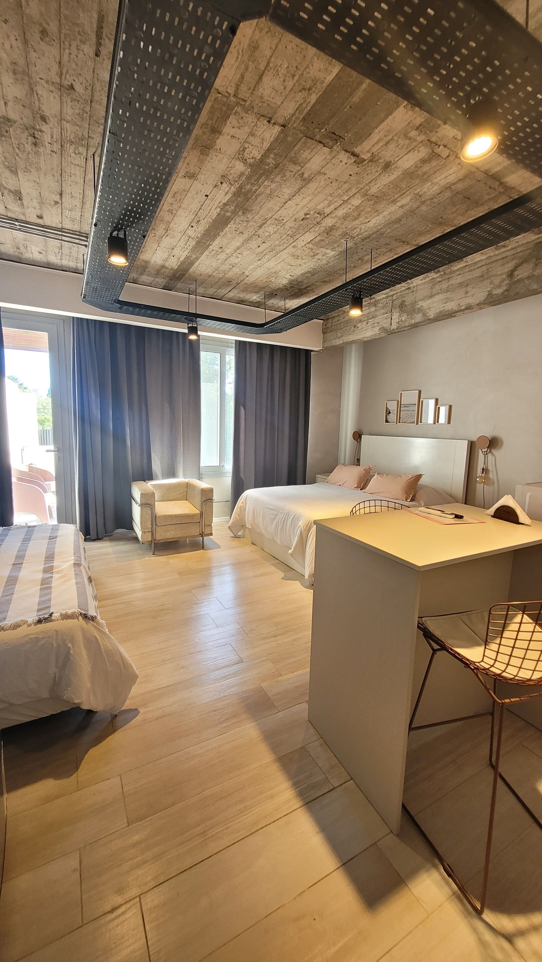 A modern bedroom with a large bed, a smaller bed, a desk, and a chair.