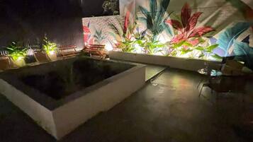 A rooftop garden with a water feature and potted plants.