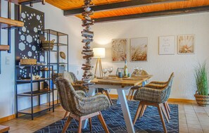 Enjoy meals in this inviting dining area with a wooden table for two, wicker chairs, and a unique wooden column.