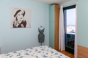 Ein Schlafzimmer mit einem Bett, einer Schneiderpuppe, einem Gemälde und einem Fenster mit Aussicht.