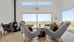 A modern living room with a large window overlooking a scenic view, a fireplace, and contemporary furniture. - Nice home in Asnæs with sauna (Asnæs)