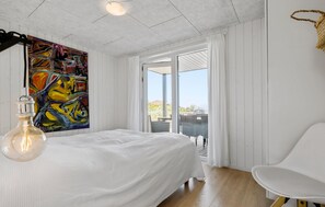 Une chambre à coucher avec un lit, une chaise, un tableau et une vue sur l’extérieur.