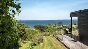 A modern house with a wooden deck overlooking a coastal landscape. - Nice home in Asnæs with sauna (Asnæs)