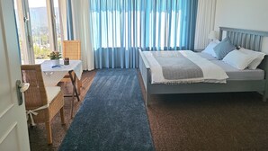 Una camera da letto con un letto, una scrivania con sedia, una finestra con tende e un lampadario.